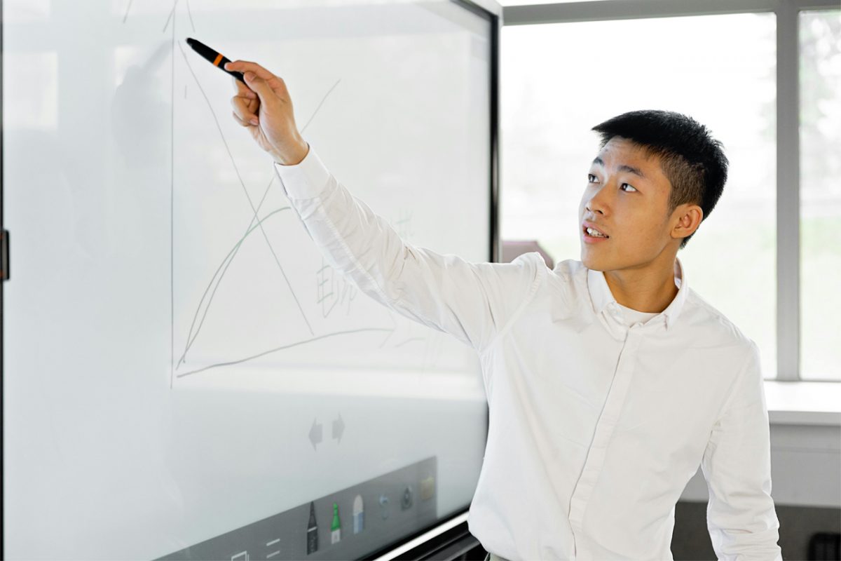 Asian American man writing on white board